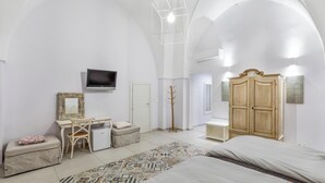 A bedroom with a bed, a desk, a wardrobe, a television, and a patterned rug. - D.Home B&B - Camera quadrupla (Oria)