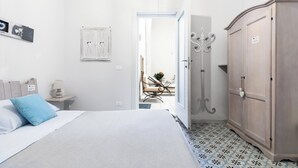A bedroom with a bed, a wardrobe, a nightstand, and a chair with a table in the background. - D.Home B&B - Camera matrimoniale (Oria)