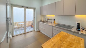 A modern kitchen with a wooden table, sliding glass doors to a balcony, and a built-in oven. - Boutique Townhouse in Fitzrovia | Pass the Keys (London)