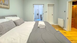 A bedroom with a bed, a door leading to a bathroom, and a poster on the wall. - Boutique Townhouse in Fitzrovia | Pass the Keys (London)