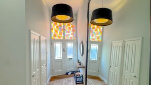 A hallway with wooden flooring, white doors, and a large mirror reflecting a colorful stained glass window. - Boutique Townhouse in Fitzrovia | Pass the Keys (London)