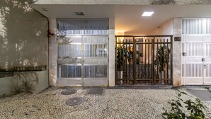 A building entrance with a tiled pavement, a metal gate, and a staircase leading to a second floor.