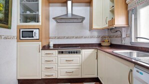 A kitchen with white cabinets, a microwave, a stove, and a sink. - Grand Beachside Apartment (Cádiz)