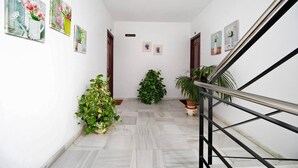 A hallway with a staircase, potted plants, and framed artwork on the walls. - Grand Beachside Apartment (Cádiz)