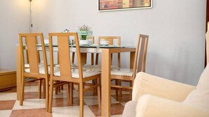 A dining area with a round table and six chairs, a floor lamp, and a framed picture on the wall. - Grand Beachside Apartment (Cádiz)