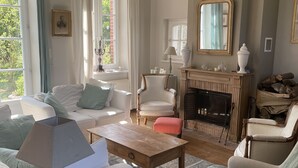 A living room with a fireplace, a sofa set, a coffee table, and a dining table.