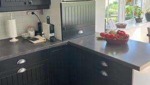 A kitchen with dark cabinetry, a microwave, and a window with a view of greenery.