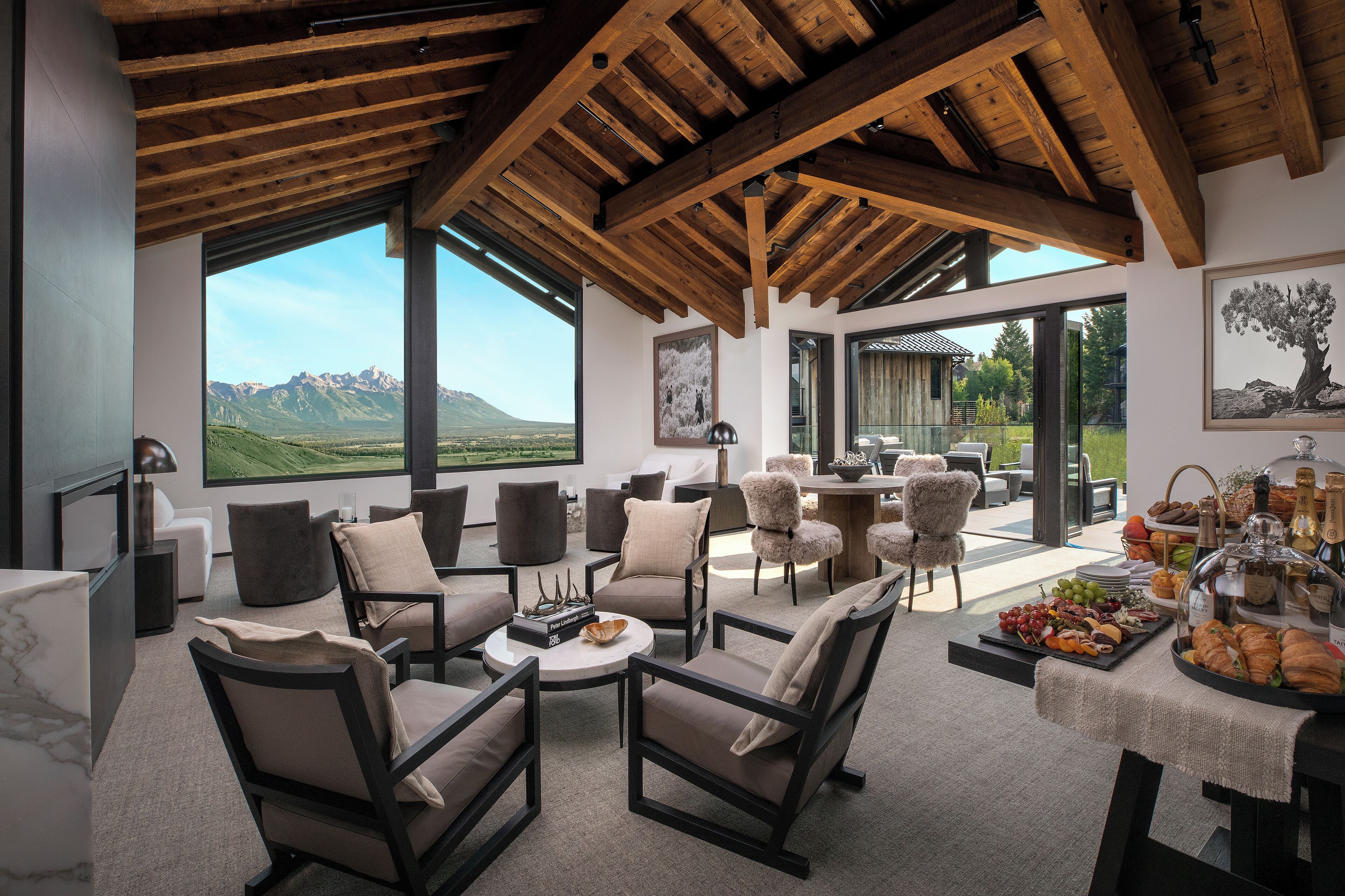 Amplia sala de estar con muebles modernos, ventanas grandes que ofrecen vistas a las montañas y un comedor con servicio de buffet.