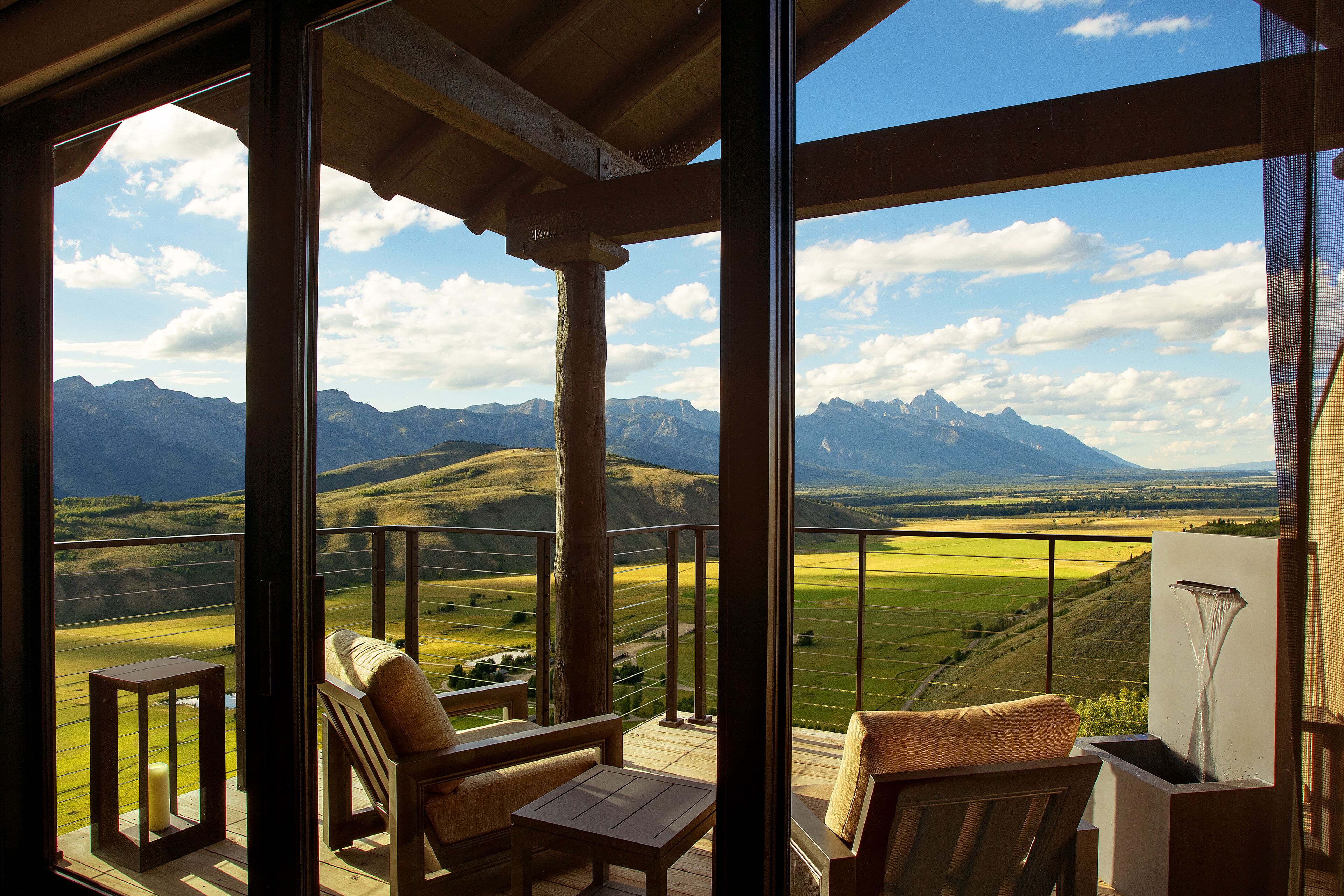A balcony with wooden furniture and a view of a mountainous landscape.