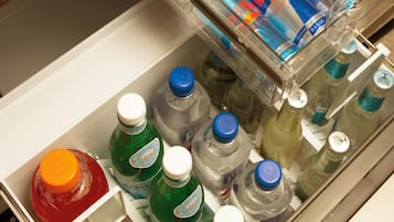 Un refrigerador con diversas bebidas, incluyendo gaseosas, bebidas energéticas y botellas de agua.
