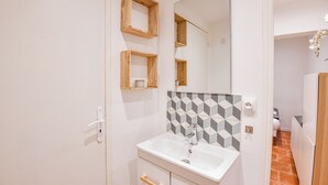 A bathroom with a white sink, wooden shelves, a geometric tile backsplash, and a mirror.