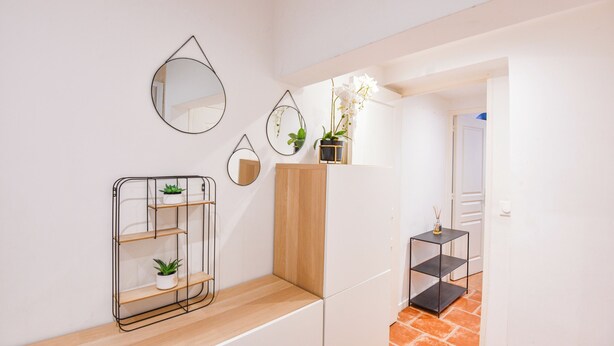 A modern interior with a wooden counter, metal shelving units, and decorative mirrors.