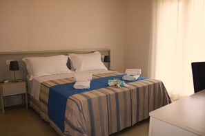 A hotel room with a bed, a nightstand, a desk, and a window with curtains. - La Bella Dimora (Otranto)