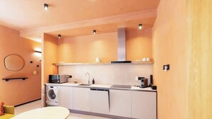 A compact kitchen with a washing machine, a microwave, a sink, and a coffee maker. - Materia Terra&Vidru Studio by Propertize (Cagliari)