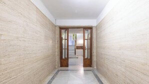 A hallway with light-colored walls and a tiled floor, leading to a staircase. - Materia Terra&Vidru Studio by Propertize (Cagliari)