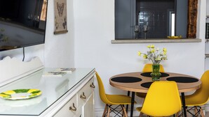 Un comedor con una mesa redonda, sillas amarillas y un aparador de vidrio.