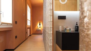 Une salle de bain moderne avec un plan de toilette noir, un luminaire fixé au mur et des articles de toilette.
