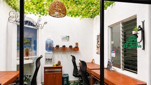 A small office space with a wooden table, black office chairs, a water dispenser, a large water bottle, and a window with a sign. - Hospedajes El Jardin (Envigado)