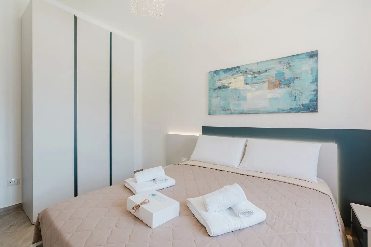 A modern bedroom with a bed, pillows, and folded towels.