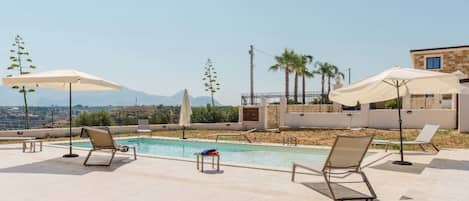 Una piscina al aire libre, sombrillas, tumbonas