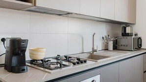A modern kitchen with a gas stove, coffee maker, and a microwave. - VILLA CON PISCINA (Balestrate)