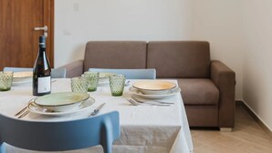 A dining table set with plates, glasses, and cutlery, a bottle of wine, and a blue chair. - VILLA CON PISCINA (Balestrate)