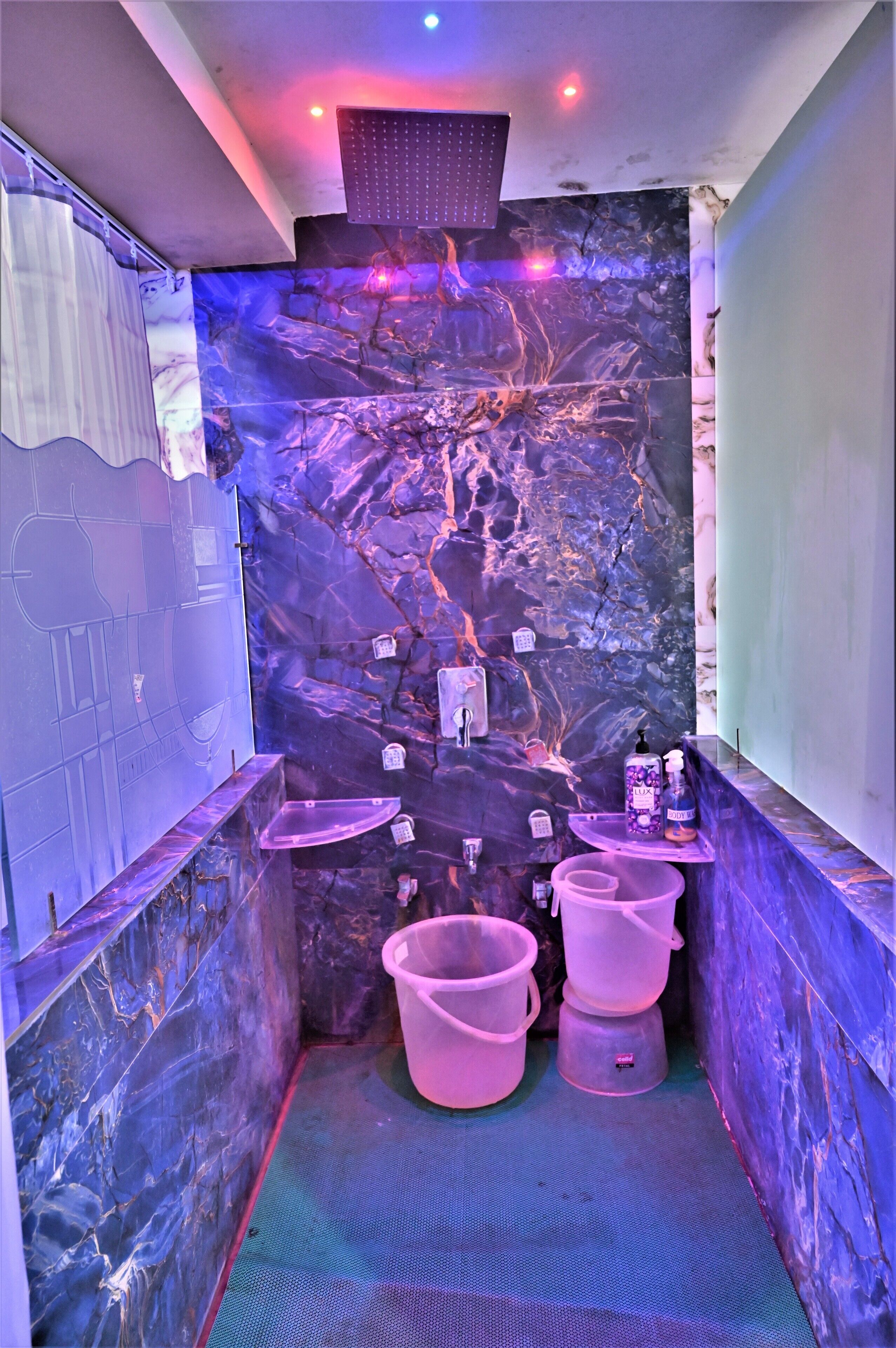 A bathroom with a marble wall, a shower, and a sink.