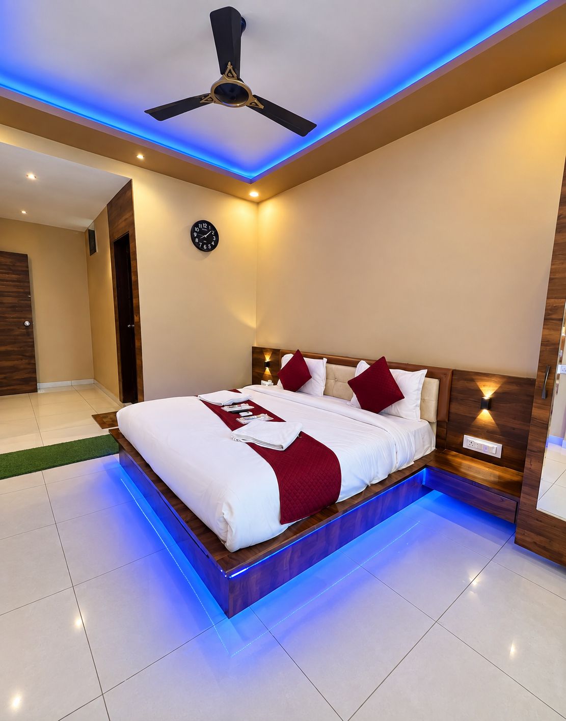 A modern bedroom with a large bed, a ceiling fan, and a wall-mounted clock.