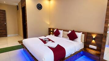 A modern bedroom with a large bed, a ceiling fan, and a wall-mounted clock.