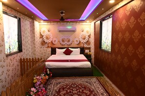 A room with a bed, floral wallpaper, a patterned rug, and a ceiling fan.