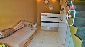 A reception area with a reception desk labeled "RECEPTION," a clock on the wall, and a "PUSH" sign on a door handle. - HOTEL ROYAL MANSION SOMNATH (Veraval)
