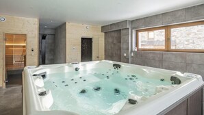 Ein modernes Badezimmer mit einer großzügigen Whirlwanne, Holzwänden und einer Wand aus Stein.