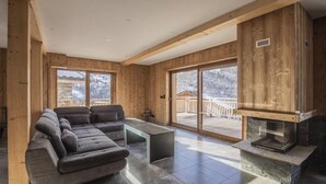 Ein modernes Wohnzimmer mit einer Eckcouch, einem Glastisch und einem Kamin.