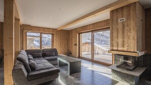 Ein modernes Wohnzimmer mit einer Eckcouch, einem Glastisch und einem Kamin.