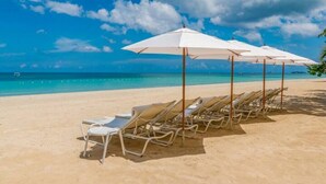 Een strand met witte parasols en ligbedden langs de kust.