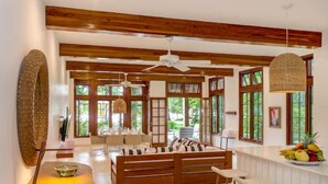 Un salón espacioso con un banco de madera, una mesa redonda y una zona de bar con taburetes.