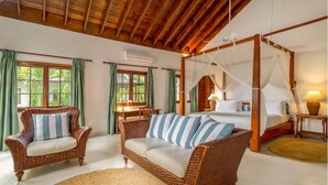 Habitación con muebles de mimbre, cama con dosel y cortinas verdes.
