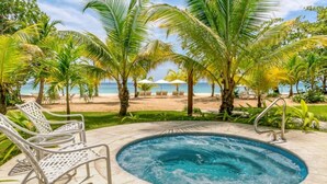 Un área de piscina con jacuzzi, sillas de descanso y vistas a la playa.