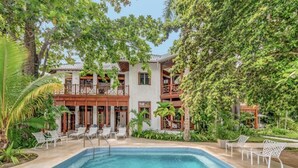 A pool area with lounge chairs and a building with balconies.