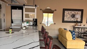 A modern kitchen with a marble countertop and a dining area with wooden chairs.