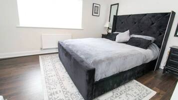 A bedroom with a large bed, a patterned rug, a radiator, and a window.