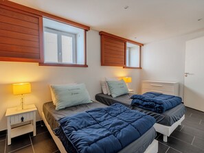 Un dormitorio con dos camas, cabeceros de madera, lámparas de noche y una ventana.