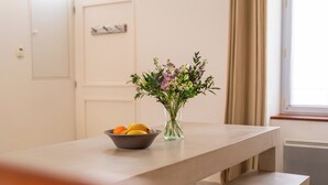 Una encimera de cocina con un bol de fruta y un jarrón de flores.