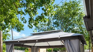 A covered patio area with outdoor furniture, a pergola, and a grassy lawn.