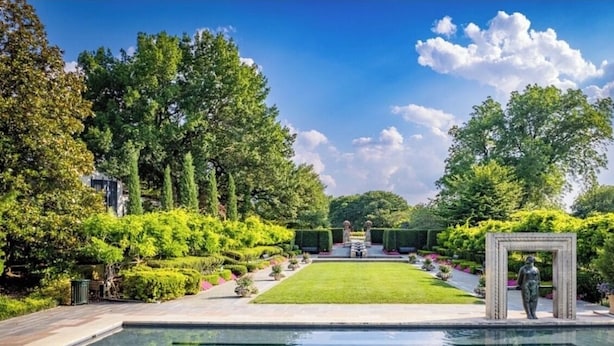 A pool with a clear view of the surrounding garden and a statue.