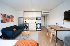 Un espacio habitable compacto con kitchenette, sofá, zona de comedor pequeña y cama.