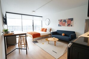 Un espacio habitable moderno y funcional con cama, sofá, comedor y cocina.