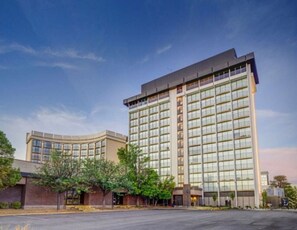 Ein modernes Hotel mit gewölbter Fassade, großen Fenstern und einem Parkplatz davor.