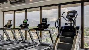 A gym with treadmills and a stair climber, large windows with a city view.