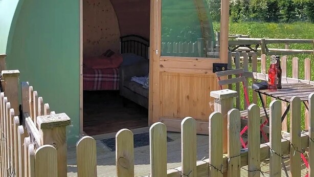 Een klein, halfrond houten bouwwerkje met de tekst 'Buzzard' erop, en een bed van binnen.